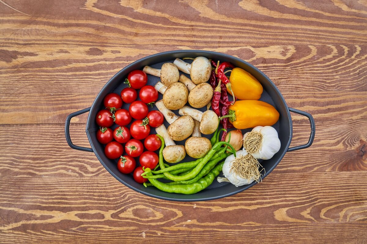 Eine Auflaufform aus Metall, die mit Tomate, Pilzen, Paprika und weiteren Gemüsen gefüllt ist.