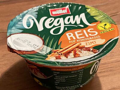 Ein Kunststoffbecher Becher Vegan Reis "Zimt" steht auf einer Fläche aus Holz.