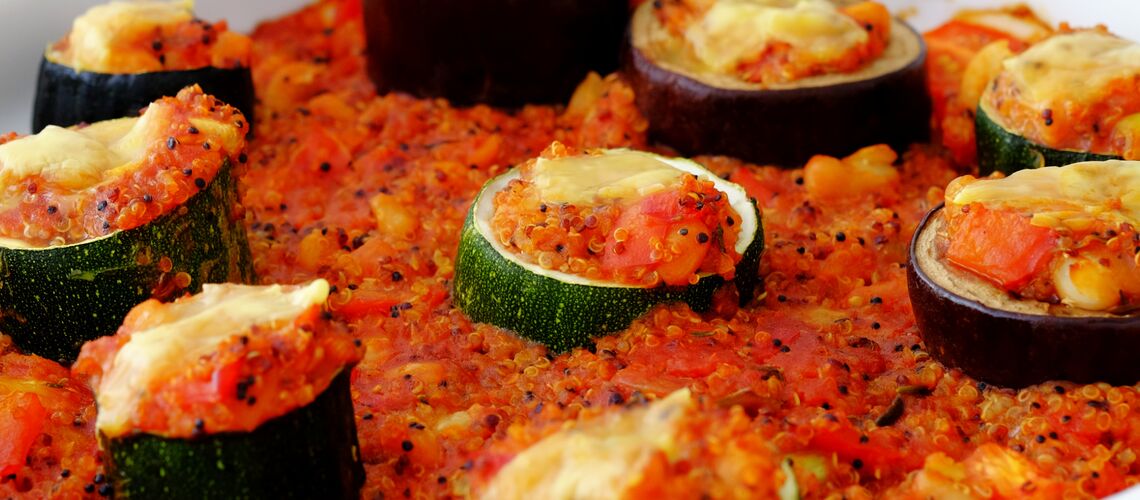 Mehrere gefüllt Gemüseröllchen in Tomatensoße in einer weißen Auflaufform.